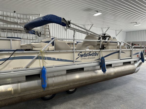 A 2005 Sweetwater 20' Pontoon is parked in a garage.