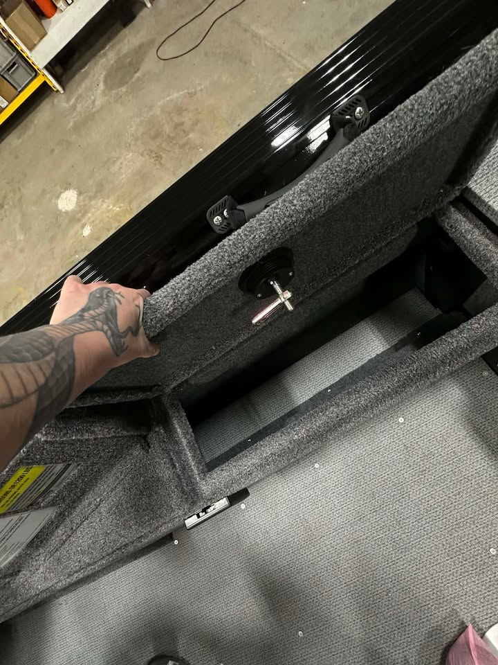 Tattooed hand opening grey carpeted storage compartment