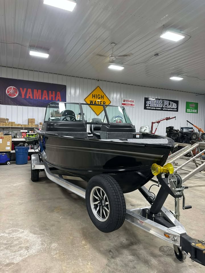 Black fishing boat on trailer in workshop