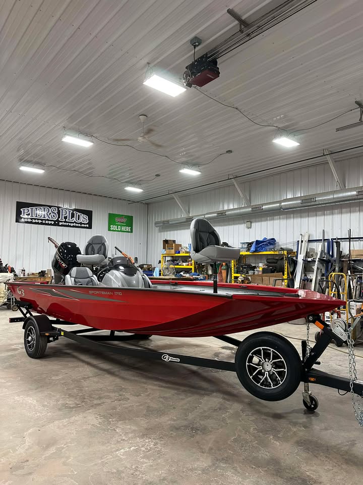 Red bass boat on trailer inside workshop