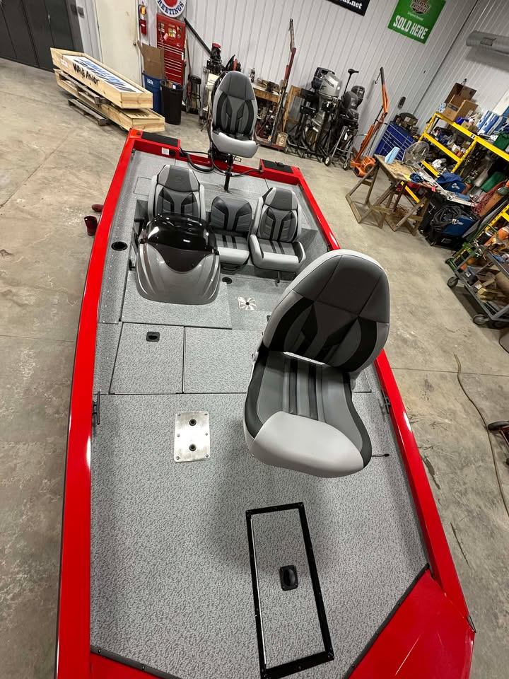 Red bass boat with gray deck in workshop