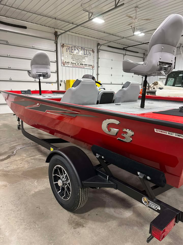 Red G3 fishing boat on trailer indoors