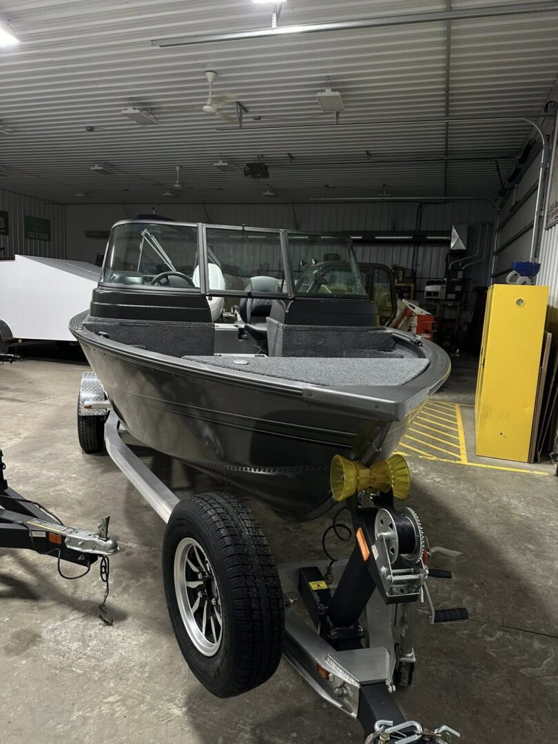 Aluminum fishing boat on trailer inside workshop